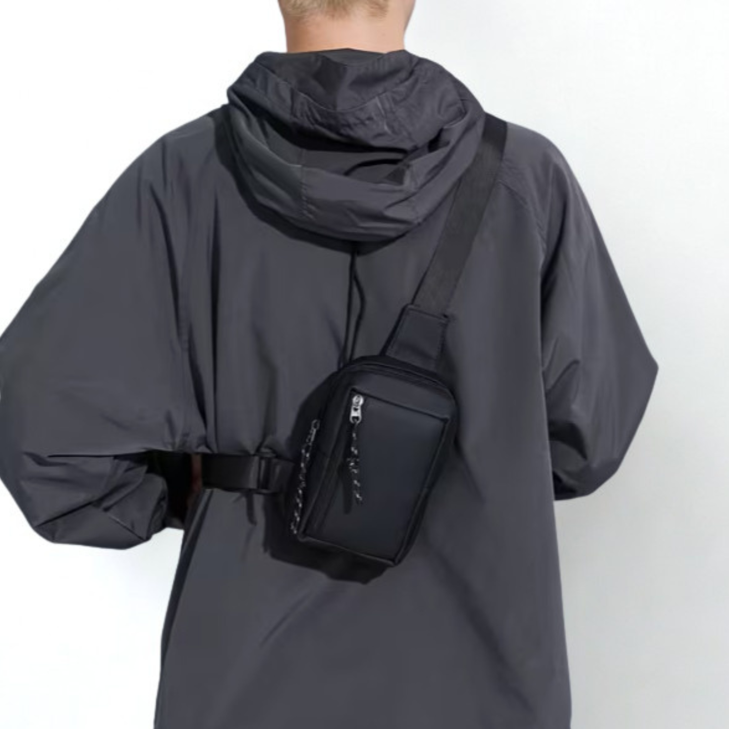 Person wearing a dark gray jacket with a black waist bag on a white background