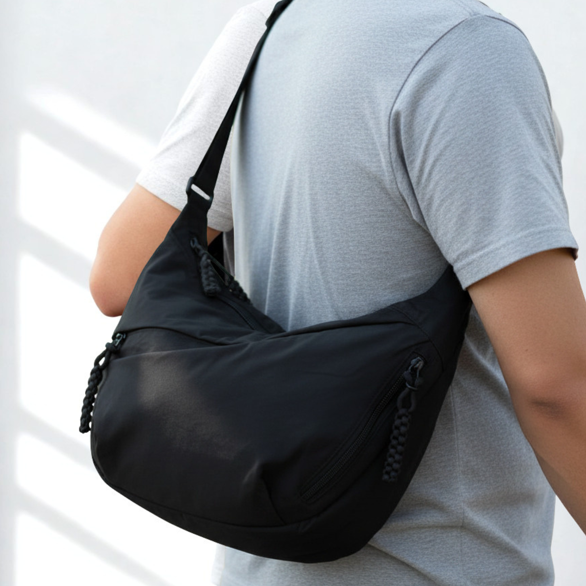 Person wearing a black shoulder bag on a light background